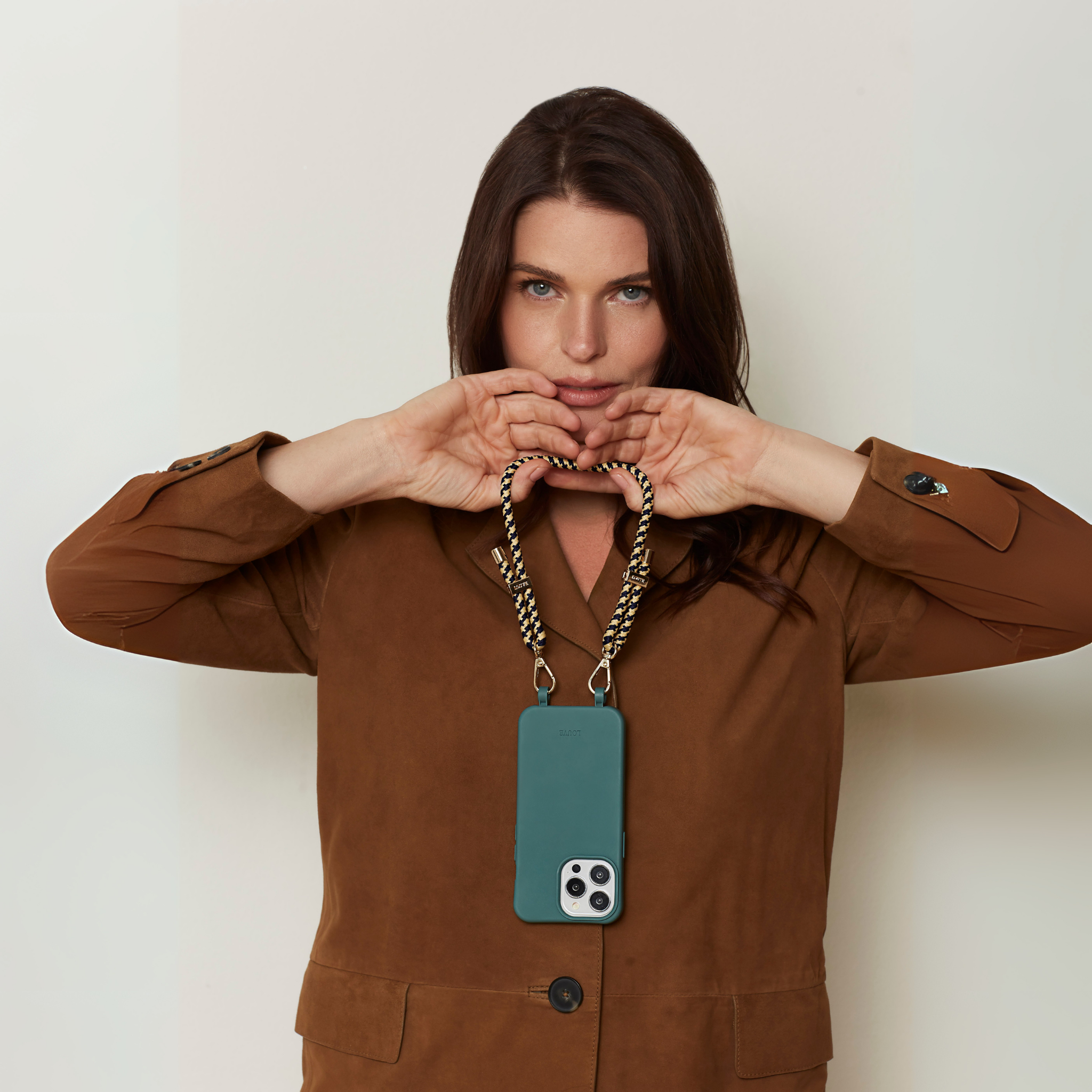 Woman holding a blue phone case with a chain strap against a plain background