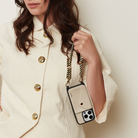 Woman holding a phone case with a chain strap against a neutral background