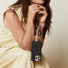 Black phone case with a lanyard held by a person wearing a yellow dress.